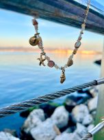 Collana charms marini e pietre naturali dettaglio al tramonto.