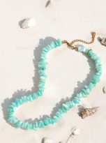 Collana con pietre naturali verde acqua posata sulla spiaggia