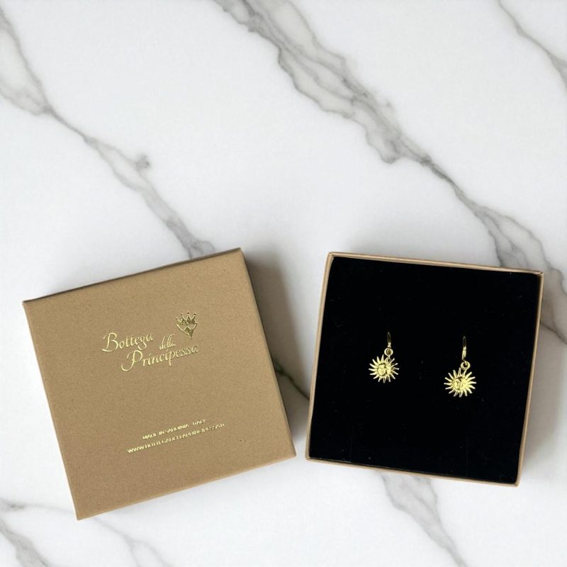 Orecchini sole dorati in acciaio inossidabile con scatola ufficiale di Bottegadella Principessa su sfondo marmo.