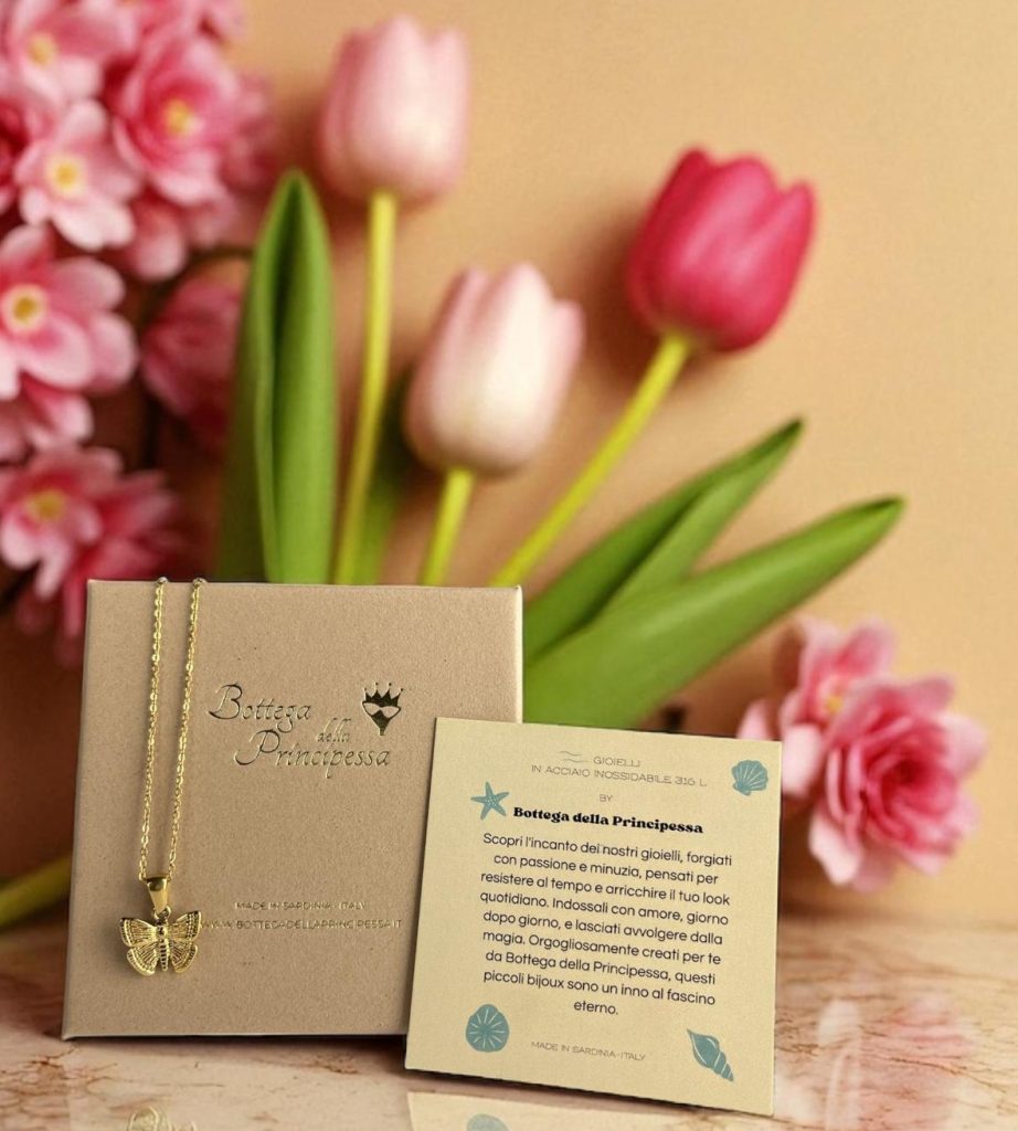 Collana con ciondolo farfalla in acciaio inossidabile oro di Bottega della Principessa, presentata in confezione regalo con bigliettino e fiori rosa, perfetta come dono elegante e simbolico.