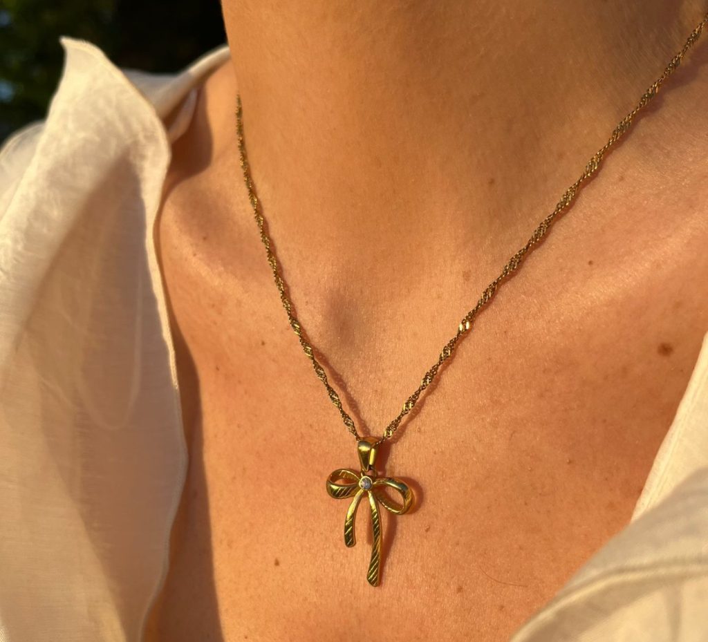 Collana fiocco in acciaio inossidabile oro indossata al collo con luce calda, stile Coquette elegante e femminile