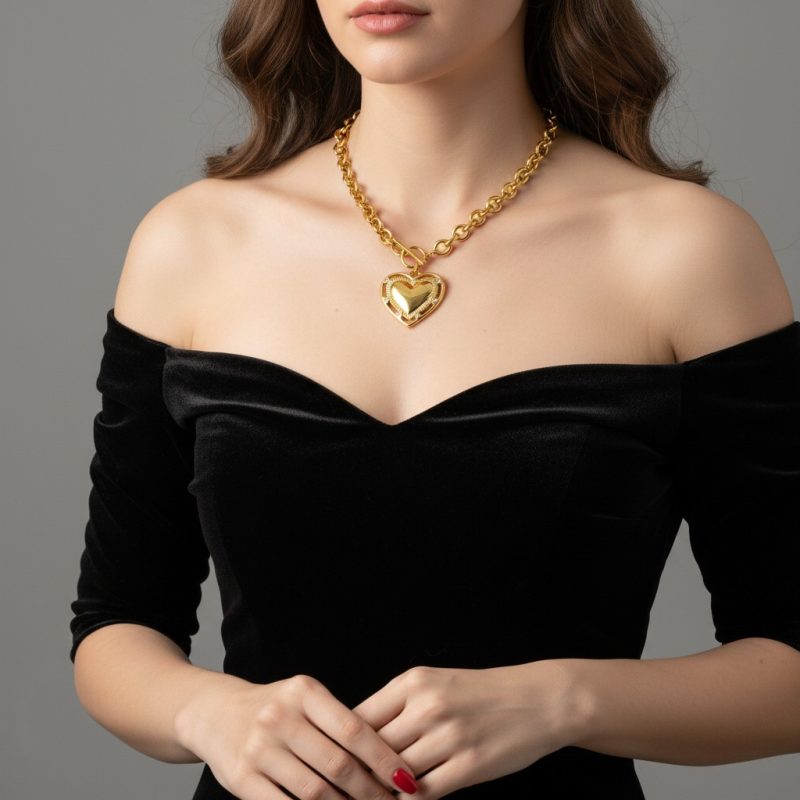 Donna con collana a cuore statement dorata in acciaio inossidabile 316L indossata su abito elegante nero