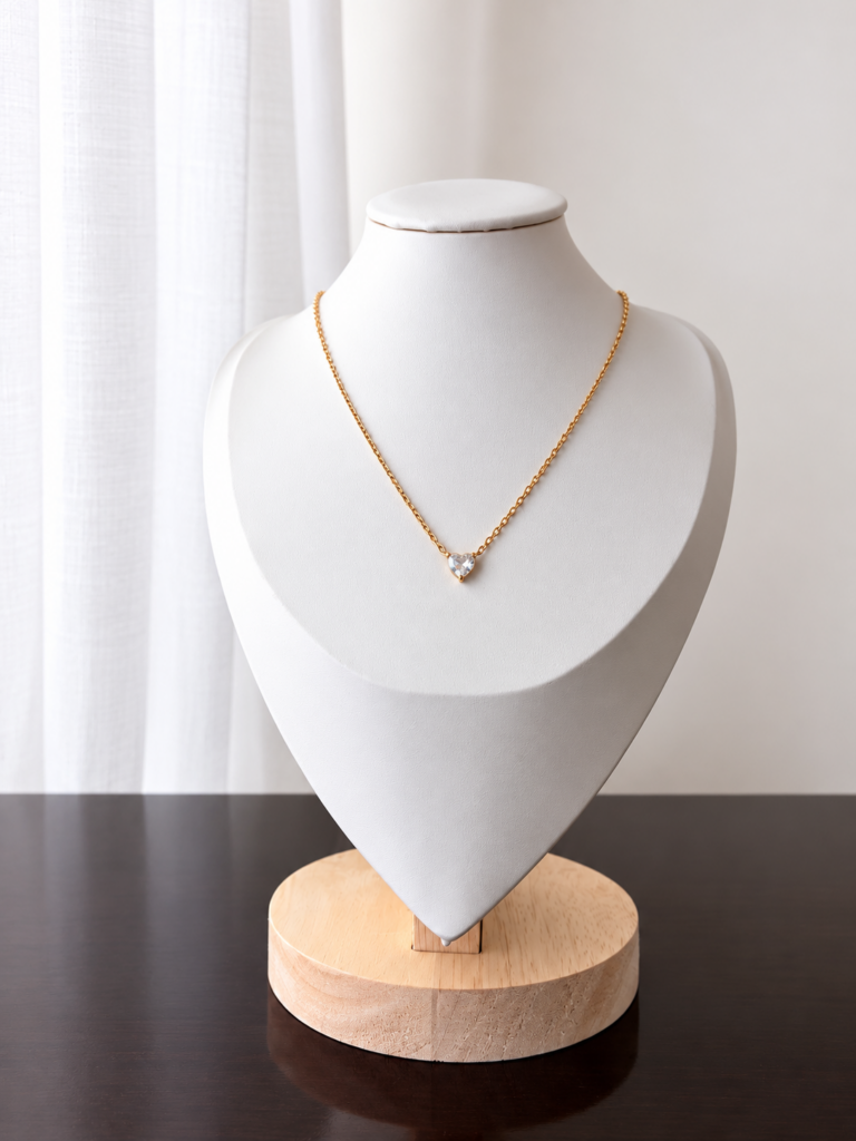 Collana dorata con piccolo cuore in cristallo trasparente su busto bianco, collezione Punto Luce di Bottega della Principessa