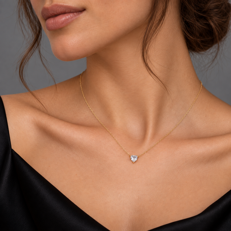 Collana Punto Luce Cuore Oro con catena dorata e pendente a cuore trasparente, indossata da modella elegante con abito nero.