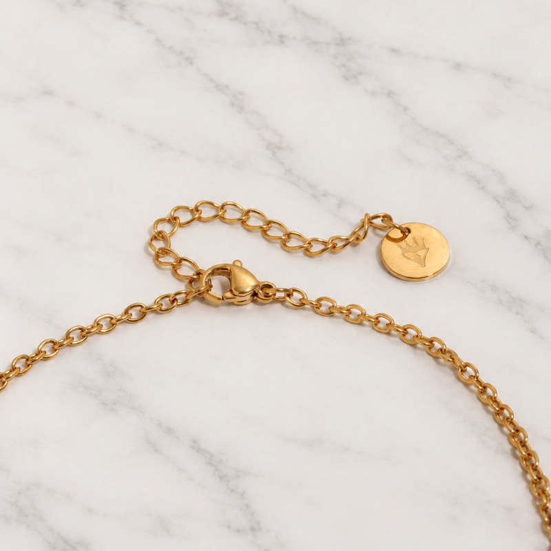 Dettaglio della chiusura regolabile della Collana Stella dorata con medaglietta logo Bottega della Principessa su marmo bianco